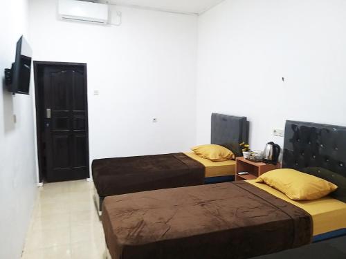 um quarto com duas camas num quarto com uma televisão em Aipayung Homestay 