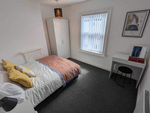 a bedroom with a bed and a desk and a window at Victoria House in Scarborough