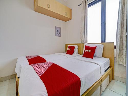 2 bedden in een kamer met rode en witte kussens bij OYO 92772 Losmen Diah Syariah in Langsa