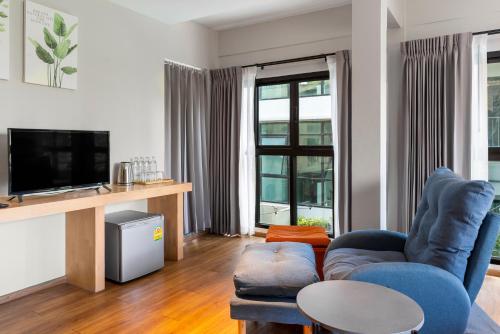 a living room with a blue couch and a tv at Nest by Sangob in Bangkok
