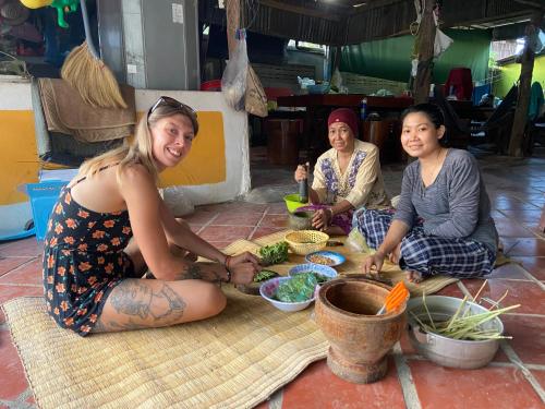 un grupo de tres mujeres sentadas en el suelo comiendo comida en Lazy Mango Home Stay, en Phumĭ Poŭthĭ Mâ Srei