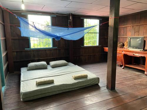 a bedroom with a bed in a room with a tv at Lazy Mango Home Stay in Phumĭ Poŭthĭ Mâ Srei