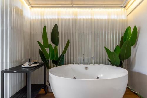 a white bath tub in a bathroom with a plant at Nest by Sangob in Bangkok