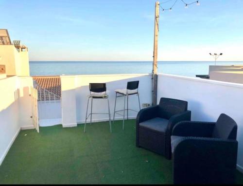 a balcony with two chairs and a bar with the ocean at Ático en la playa con terraza privada in Cala del Moral