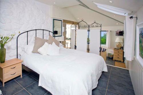 a bedroom with a large white bed with white pillows at Basking Shark, Studio Cottage With Superb Sea Views By Beach in Sennen