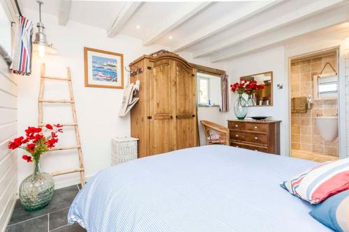 a bedroom with a bed and a bathroom with a ladder at Sandpipers, Boutique Cottage With Wow Sea Views In Amazing Location in Sennen