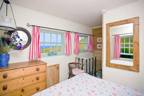 a bedroom with a bed and a dresser and a mirror at Little Petra, Cottage With Garden, Superb SeaViews in Amazing Location in Sennen