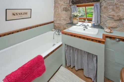 a bathroom with a sink and a counter with a window at White Rose, Cornish Cottage With Sea Views & Private Garden By Beach in Sennen