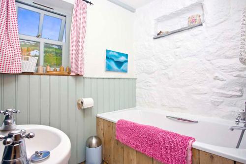 uma casa de banho com uma banheira e um lavatório em Little Petra, Cottage With Garden, Superb SeaViews in Amazing Location em Sennen