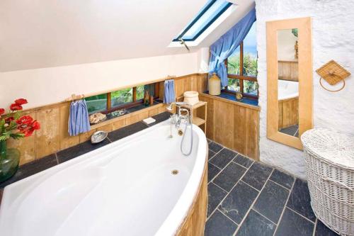 baño grande con bañera y ventana en Penrose, Cornish Cottage With Sea Views, Garden & Patio By the Beach, en Sennen