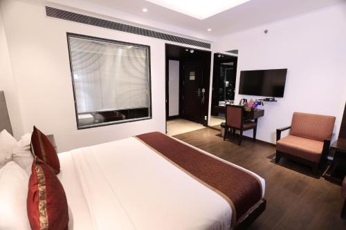 a bedroom with a bed and a desk and a television at Hotel Godwin Deluxe - Free Airport Pick-Up in New Delhi