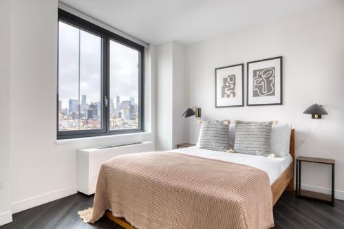 a white bedroom with a bed and a large window at 1BR in Hip E Village w Doorman Gym NYC-150 in New York