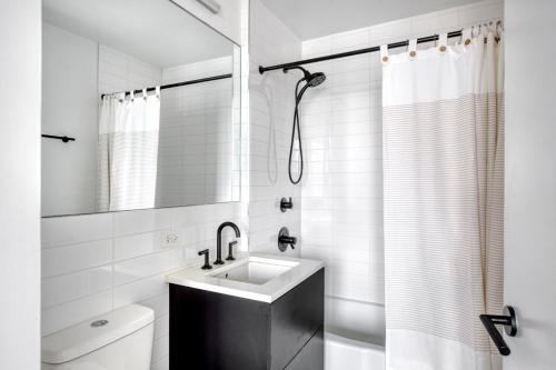 uma casa de banho branca com um lavatório e um chuveiro em 1BR in Hip E Village w Doorman Gym NYC-150 em Nova York