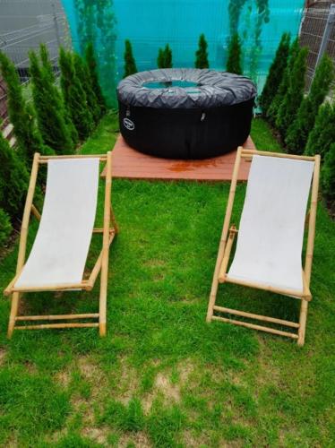 two chairs sitting in the grass next to a tire at Apartament Japko in Gliwice