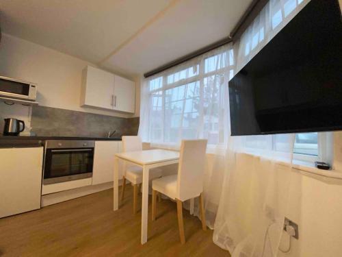 eine Küche mit einem Tisch mit Stühlen und einem TV in der Unterkunft Spacious Studio 30 mins from Luton free parking in The Hyde