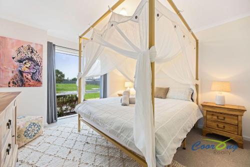 River Dais في Wellington East: غرفة نوم مع سرير مظلة ونافذة