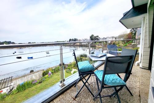 een balkon met een tafel en stoelen en uitzicht op het water bij Appartement Terrasse - Vue Imprenable sur le Golfe in Larmor-Baden