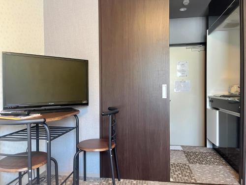 a room with a desk with two stools and a television at Miro Kyoto Nijo Hotel in Kyoto