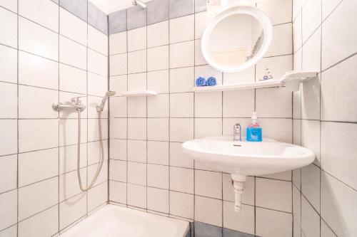W białej łazience znajduje się umywalka i lustro. w obiekcie Pavlos Sofia Studio w mieście Ágios Matthaíos