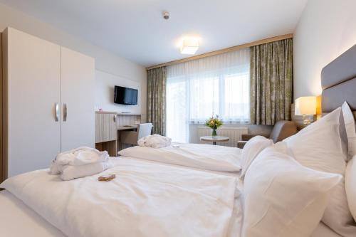 a hotel room with two beds with white sheets at Hotel-Restaurant Grimmingblick in Bad Mitterndorf