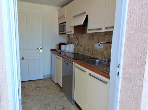 eine kleine Küche mit weißen Schränken und einem Waschbecken in der Unterkunft Appartement 10 en duplex - LES SUITES DE ROBINSON - Résidence avec piscine en bord de Siagne, à Mandelieu-La-Napoule in Mandelieu-la-Napoule