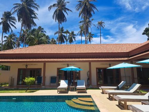 a resort with a swimming pool with chairs and umbrellas at Laura's Guest House-adult only- in Lamai