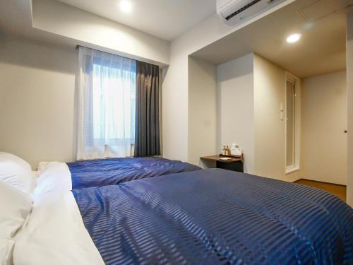 a bedroom with a blue bed and a window at HOTEL LiVEMAX Tokyo Bakurocho in Tokyo