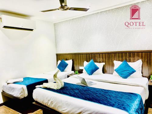 two beds in a hotel room with blue and white pillows at Qotel Hotel Rajouri Garden Above Ritu Marbles, Near Rajouri Garden Metro Station-Couple Friendly in New Delhi