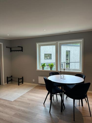 a dining room with a table and chairs and two windows at Apartment Ormestad in Uddevalla