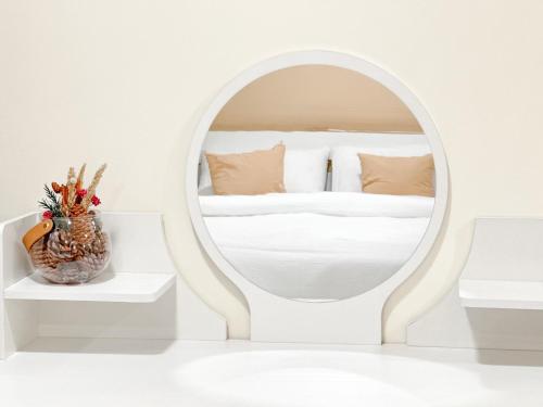 Dormitorio blanco con espejo y cama en Happiness Sleep, en Thung Si Kan