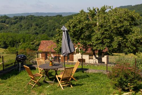 une table et des chaises avec un parasol dans l'herbe dans l'établissement Tour Milou, à Beynac-et-Cazenac