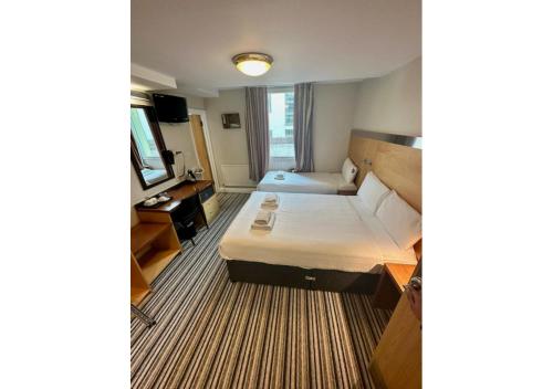 um quarto de hotel com uma cama e uma televisão em Maiden Oval em Londres