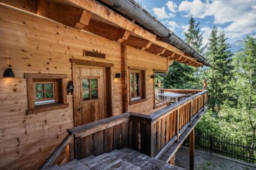 a log cabin with a porch and a deck at Wuidererhüttn, Charlet in Alleinlage mit freistehendem Saunahaus in Großkirchheim