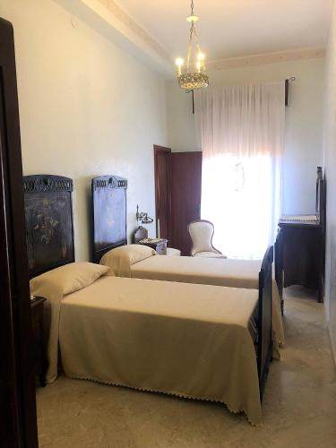 um quarto com 2 camas, uma janela e um lustre em Borgo Marina Vecchia Avola em Avola