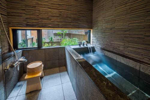 a bathroom with a tub with a toilet and a sink at Suo an Machiya House in Kyoto