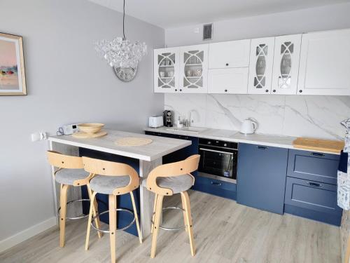 クリニツァ・モルスカにあるLuksusowy Apartament Stella - Port Krynica Morskaのキッチン(青いキャビネット、カウンター、スツール付)