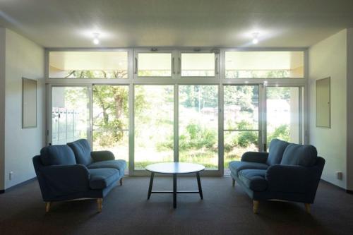 a living room with two couches and a table and windows at 松代棚田ハウス 