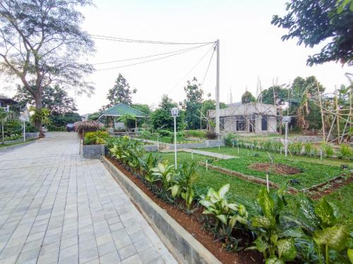 a garden with a walkway and some plants at RedDoorz at Batutulis Bogor Villa Papatong by M in Bogor