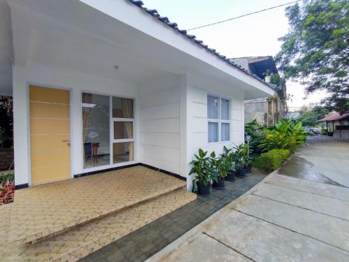 a white house with plants in front of it at RedDoorz at Batutulis Bogor Villa Papatong by M in Bogor