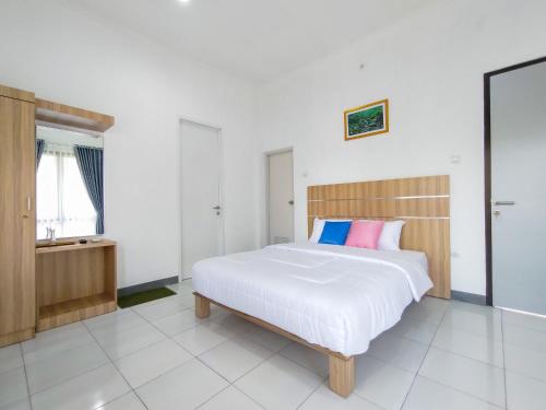 ein Schlafzimmer mit einem großen weißen Bett mit bunten Kissen in der Unterkunft Villa Papatong by M Bogor Mitra RedDoorz in Bogor