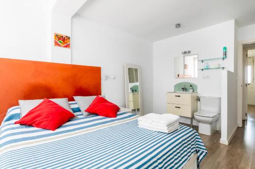 1 dormitorio con 1 cama con almohadas rojas y blancas en Fantástico apartamento en primerísima línea playa, en La Torre