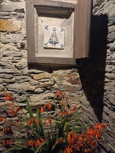 a sign on a stone wall with flowers in front of it at El Lagar de Luarca in Luarca