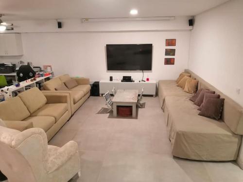 a living room with couches and a flat screen tv at Preciosa casa de lujo con piscina-150m de la playa in Almería