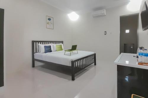 ein Schlafzimmer mit einem Bett mit einem Stuhl darauf in der Unterkunft Urbanview Hotel MM Indramayu by RedDoorz in Indramayu