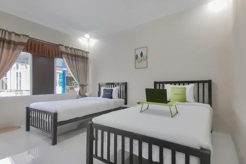 1 Schlafzimmer mit 2 Betten und einem grünen Stuhl in der Unterkunft Urbanview Hotel MM Indramayu by RedDoorz in Indramayu