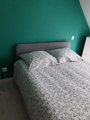 a bed in a bedroom with a blue wall at Cœur de ville, chambre confortable à louer en Bretagne in Saint-Méen-le-Grand