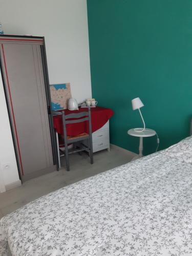 a bedroom with a bed and a table and a chair at Cœur de ville, chambre confortable à louer en Bretagne in Saint-Méen-le-Grand