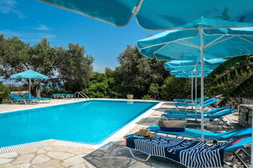 a swimming pool with blue umbrellas and chairs next to a pool at Anemona studio E in Katelios