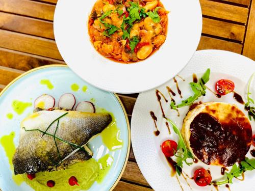 three plates of food on a wooden table at WHITE DONKEY BOUTIQUE Hotel in Chrani