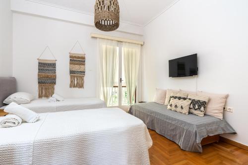 a bedroom with two beds and a tv on the wall at Villa Antiope Saronida in Saronida
